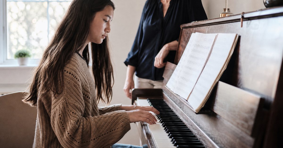 When should a serious student upgrade from a digital keyboard to a fine acoustic piano?